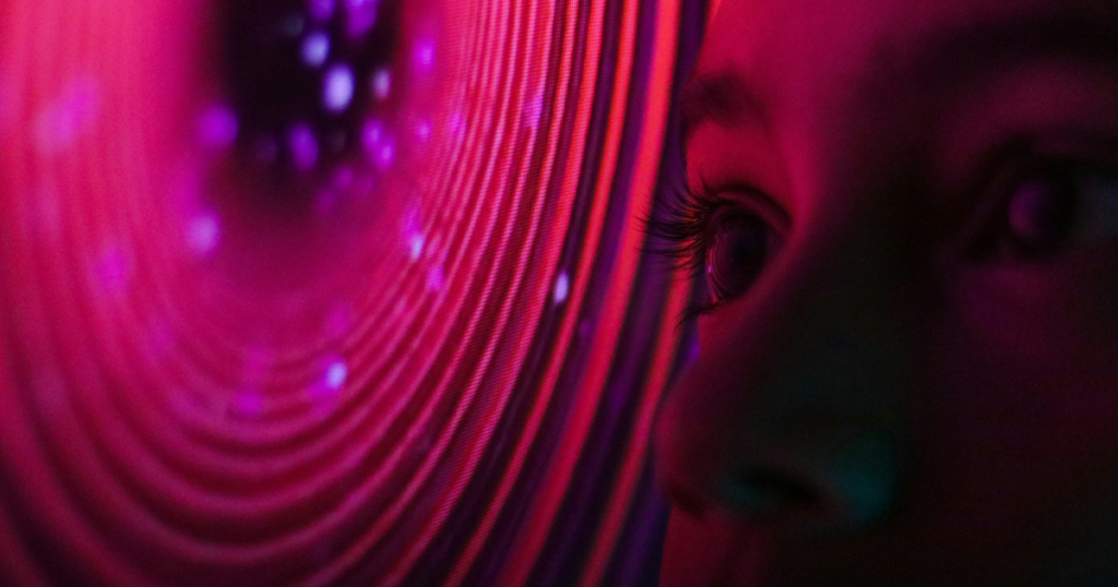 Close-up of an eye gazing into a swirling vortex of vibrant pink light and digital dots, illustrating the visualization of data by an Artificial Intelligence photo generator.