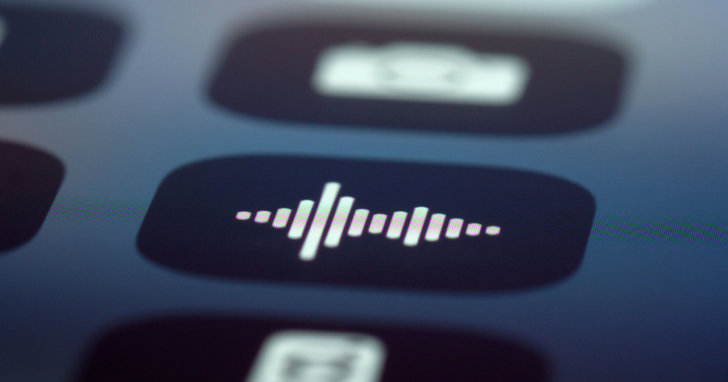 Close-up of a smartphone screen showing a white sound wave icon, representing the voice-command interface used to prompt an Artificial Intelligence photo generator.